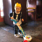 toddler boy wearing gold crown pushing vacuum toy on his birthday