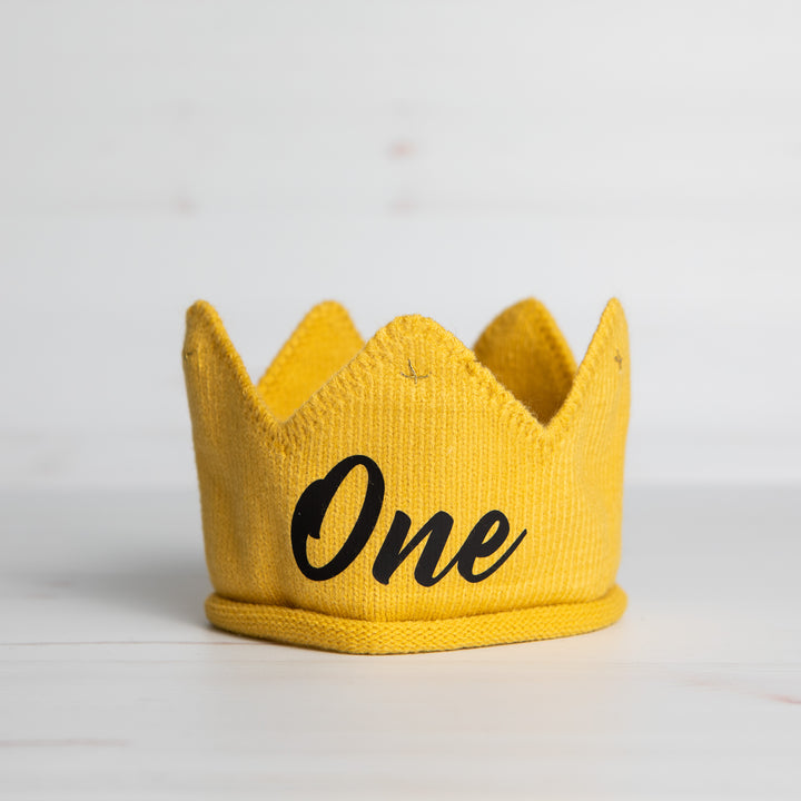 Knitted gold crown with One in black lettering and gold accents