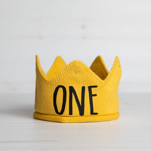 Gold knitted crown with ONE in black script lettering and gold accents