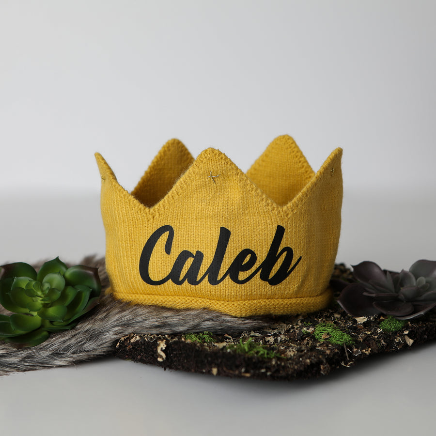 Gold knitted crown with Caleb in black lettering and gold accents