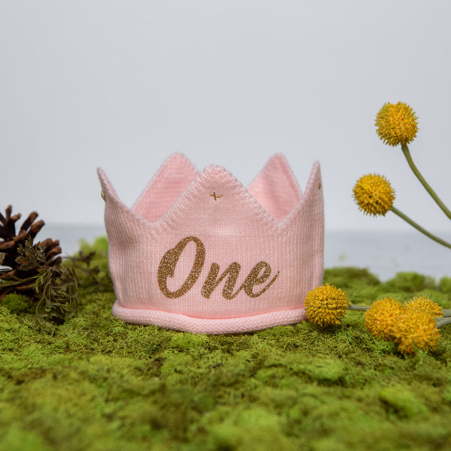 Pink knitted crown with One in gold lettering and gold accents